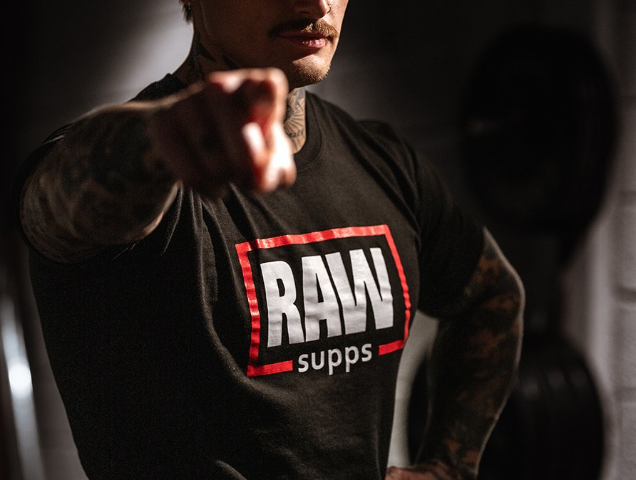 En person som har en RAW SUPPS Logo Tee p i et trningscenter.